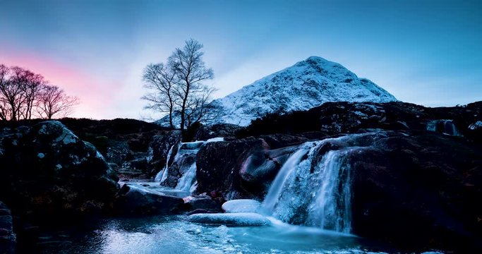 timelapse footage of a waterfall in the river coupall at the foot of buchaille etive mor in glen coe in the remote highlands of scotland during winter with ice and snow on the mountain tops