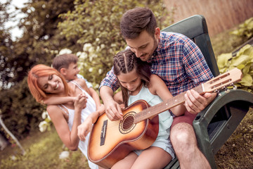 Fototapeta premium Dad playing guitar for the family in the garden
