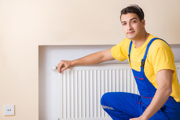 Young repairman contractor repairing heating panel 