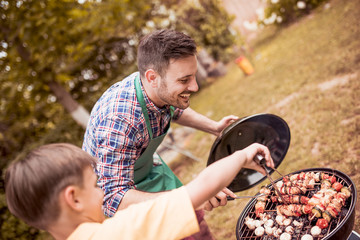 Father and son having a barbecue party in their garden in summer.