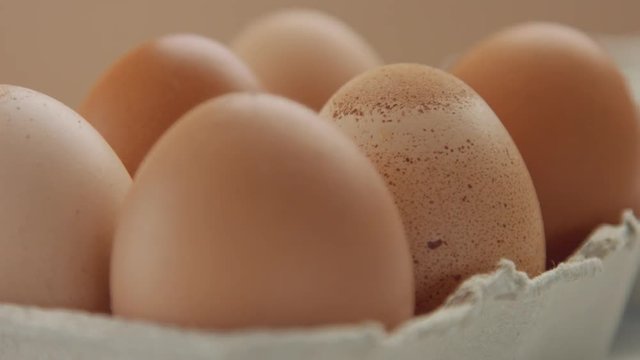 closeup of six brown eggs and woman's hand take off one of it