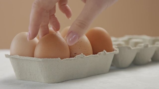 woman's hand put an egg box in perspective open it and take out one brown egg