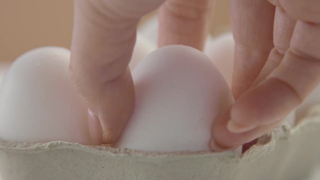 closeup of white egg and wmans hand take it out from the box. slow motion from 60fps
