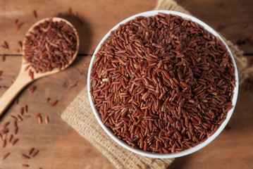 Rice berry in white bowl on wood background