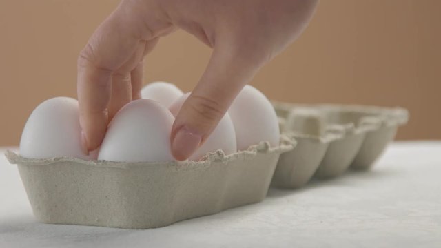 woman's hand put an egg box in perspective open it and take out one white egg