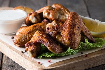 Close-up photo of bbq chicken wings with fries and beer. Barbeques meat with sauces, ketchup, mayonnaise. Fast and junk food concept. 