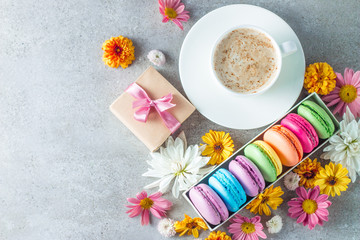 Obraz na płótnie Canvas Photo of cake macarons, gift box, tea, coffee, cappuccino and flowers. Sweet romantic food macaroon concept. Morning breakfast and presents.