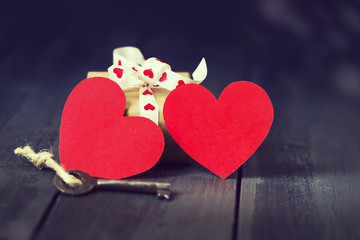 Red paper heart old key and presents on a dark wooden background. St. Valentine's Day. Copy space.