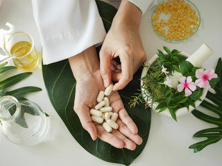 scientist or doctor making herbal medicine with herb leaves , capsule, tablets. hands.top view.