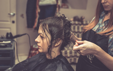 A professional hairdresser cuts hair to a woman in a beauty salon. The process of creating a stylish hairstyle.