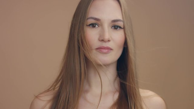 slowmotion front view portrait of woman looking at camera. Brown eyes, straight blonde hair