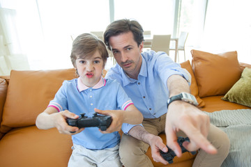 Father and son playing videogame at home