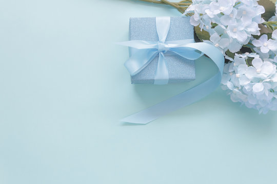Top view aerial image of decoration Happy mother’s day holiday background concept.Flat lay gift box with blue flower on modern beautiful  blue paper at home office desk.Free space for design.