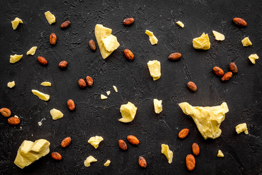 Scattered cocoa butter pieces and cococa grains. Cosmetics with natural ingredient. Black background top view