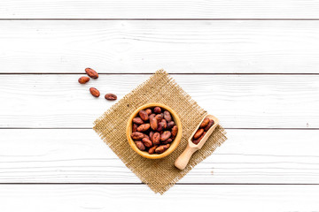 Roasted cocoa beans on white wooden background top view copy space. Raw material for cocoa powder. African or Latin American product