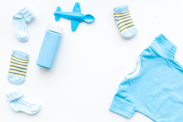 Blue set for newborn boy. Baby bodysuit, socks, airplan toy and powder on white background top view copy space