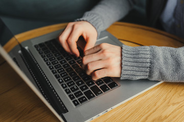 Closeup of male arm, typing on laptop, job search, job online, in a cafe with a laptop, fingers press the button