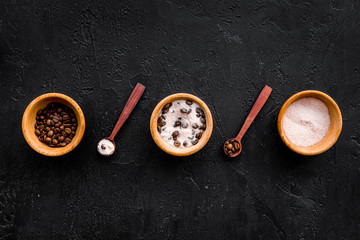 Cosmetics for skin care and relaxation. Chocolate brown spa salt on black background top view copy space