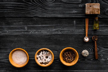 Cosmetics for skin care and relaxation. Chocolate brown spa salt on dark wooden background top view copy space