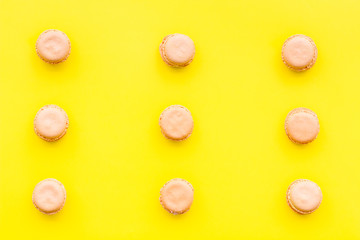Macarons dessert. Pattern on yellow pastel background top view