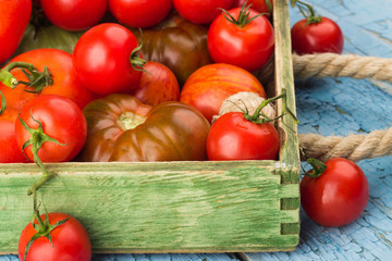 Set of different ripe tomatoes in the wooden tray