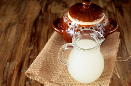 Milk whey in a glass jug and a clay pot in the background