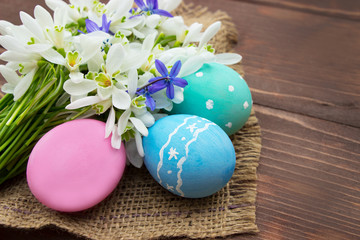Obraz na płótnie Canvas Ester background.Easter colored eggs and snowdrops flowers on wooden table.Template for greeting card