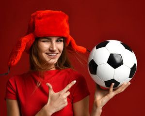Russian style fan sport woman player in red uniform and ear-flap hat hold soccer ball celebrating happy smiling © Dmitry Lobanov