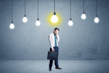 Obraz premium Businessman standing uninspired with bulbs above