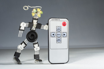 The funny robot from microcircuits and transistors holds remote control