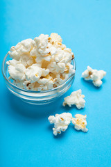 Popcorn in glass bowl on blue background.