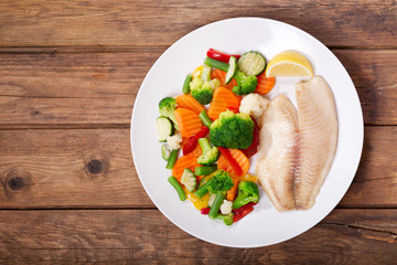 plate of fried fish fillet with vegetables, top view