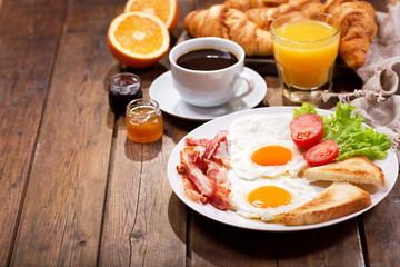 breakfast with fried eggs, croissants, juice, coffee and fruits