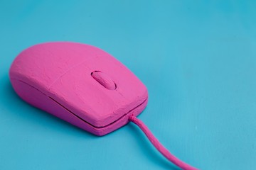 Bright pink computer mouse on blue background, copy space