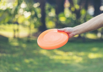Hand man throwing a frisbee disk in the park - obrazy, fototapety, plakaty