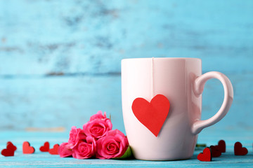 Cup of tea with red hearts and roses on wooden table