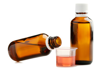 Bottles and measuring plastic cup with medical syrup on white background