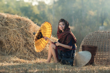 Naklejka na ściany i meble Beautiful Thai girl in Thai costume,Asian woman wearing traditional Thai culture with umbrella at farmland.