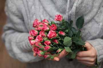 bouquet of bush of roses in female hands on a background 