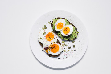 sandwich with fresh vegetables, avocado, hard-boiled eggs and pumpkin seeds with olive oil and bread. healthy diet or vegetarian food on a white background. salad with yolks on toast. top view
