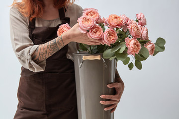 A bouquet of pink roses in girls hands wearing in apron