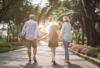 Happy family mother father and daughter walk on nature on sunset hold hand