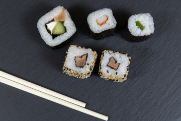 Sushi with chopsticks on black background