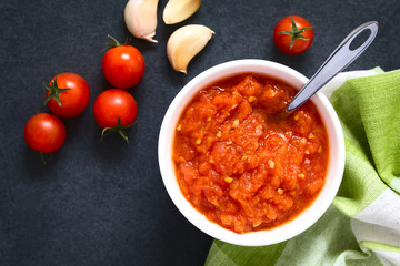 Homemade traditional Italian marinara or pomodoro tomato sauce made of fresh tomato, garlic, dried oregano and salt, photographed overhead with natural light (Selective Focus on the sauce)