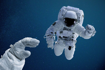 Obraz na płótnie Canvas Astronaut reaching out for colleague during space walk 