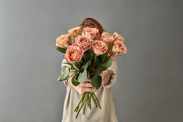A woman gives a bouquet of beige roses