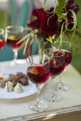 Chocolate truffles candys and glasses with red wine on white wooden table