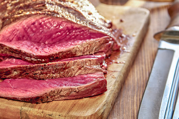 Roasted meat with blood. Well-Done juicy Steak closeup. Half-baked barbecue. Wooden background. Selective focus.
