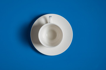 empty coffee cup and dish on blue coloured background