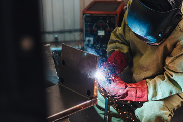 Welding concept. Industrial worker or welder wears protective mask and gloves erects technical...